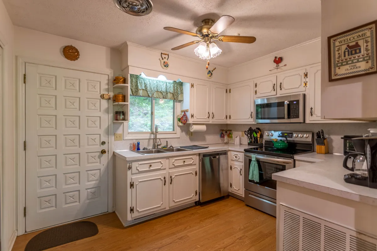 This image showcases a cozy, inviting kitchen complete with kitchen cabinets, stainless steel appliances, and a window adorned with green curtains. The scene captures the essence of meal preparation and communal gatherings, suggesting a well-equipped space perfect for cooking and sharing family stories.